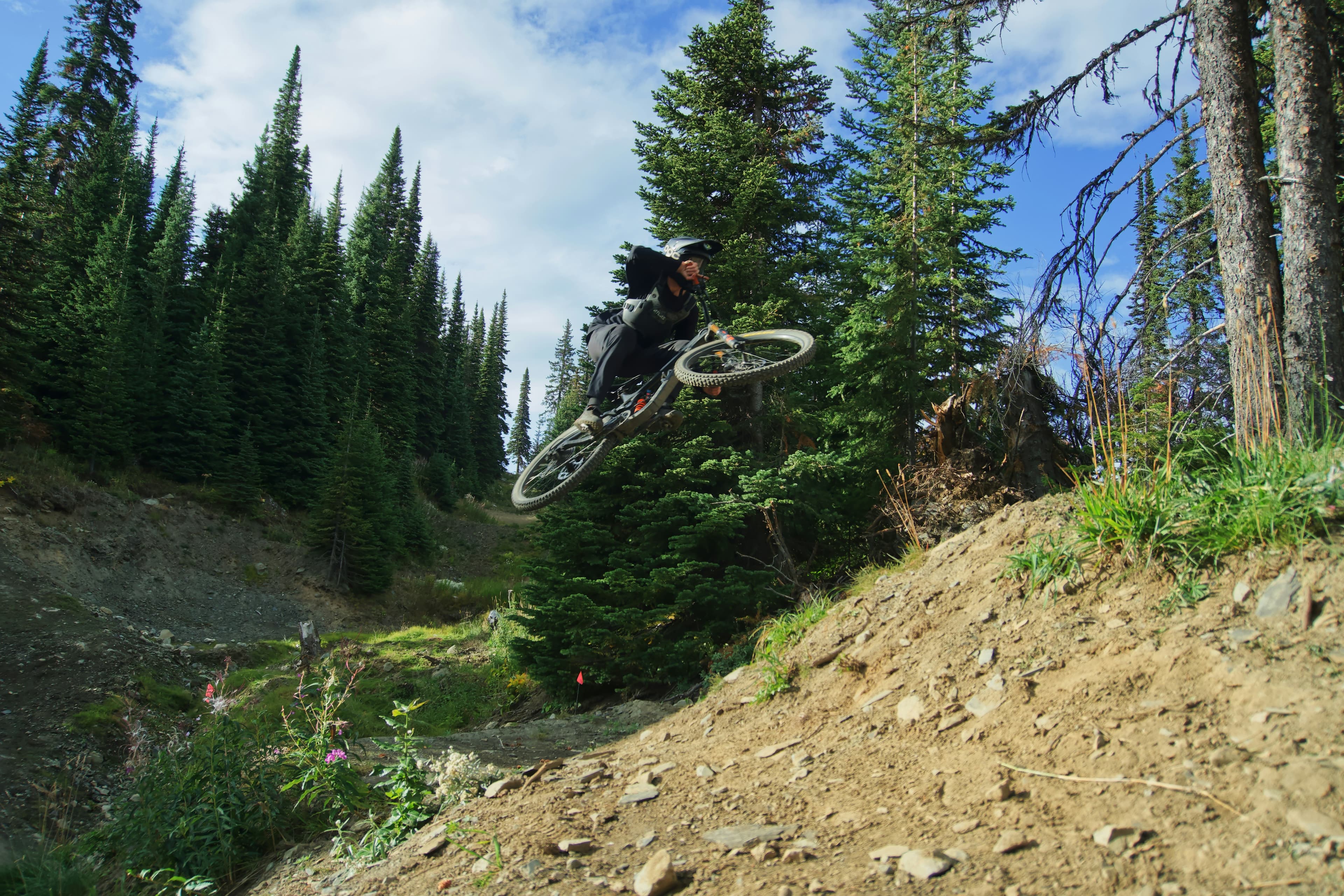 A person mountain biking in Sun Peaks' vast trail network and having hit a jump