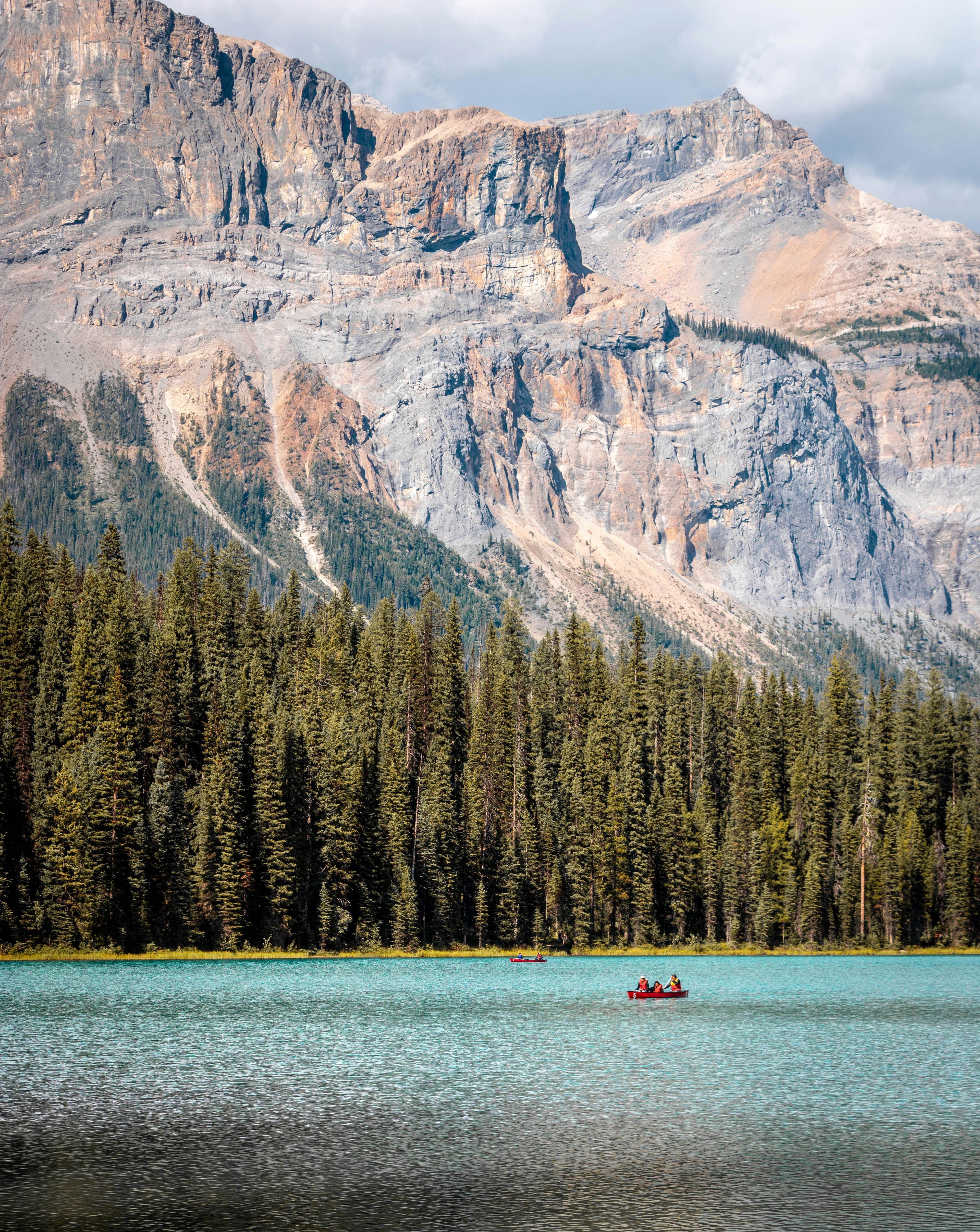 Canoers and paddlers on a lake with a large rocky mountain behind