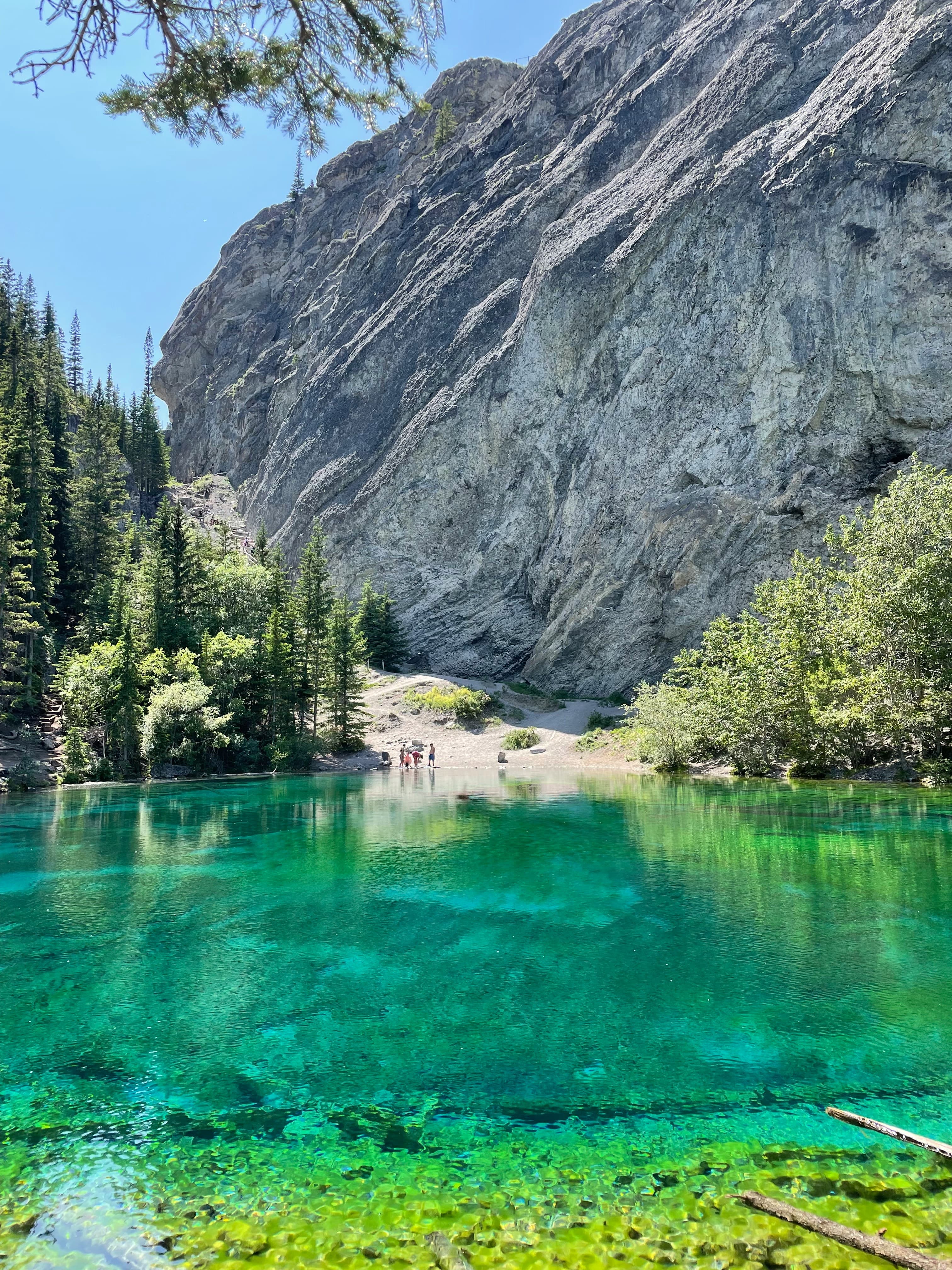 The clear turquoise Grassi Lakes surrounded by mountains with people on the other shore