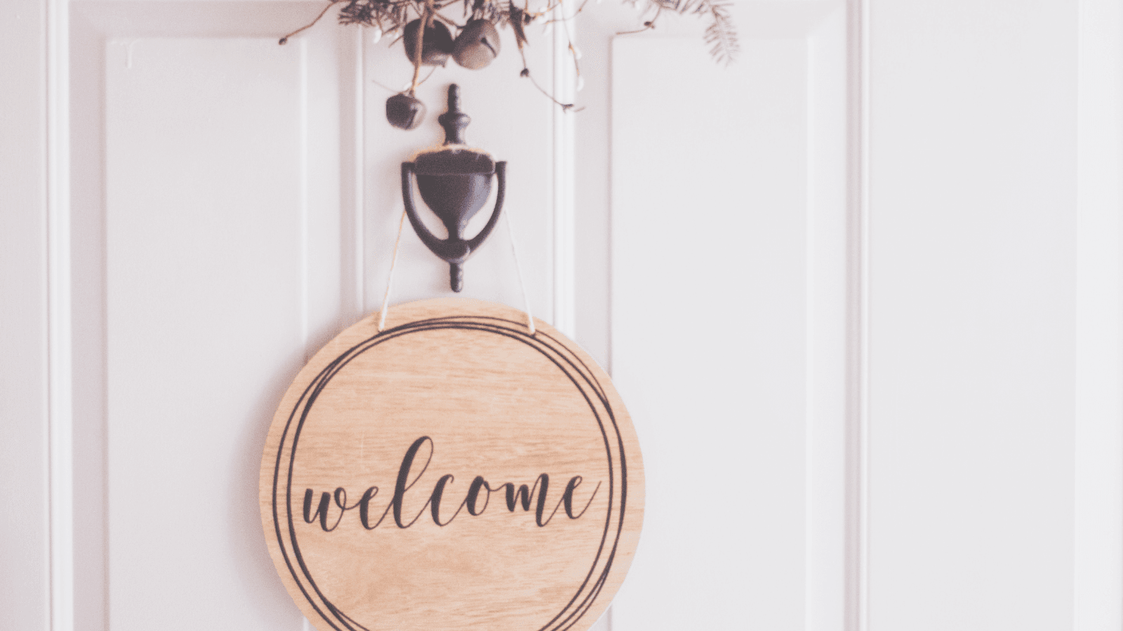 Wooden welcome sign hanging on the front door of a home